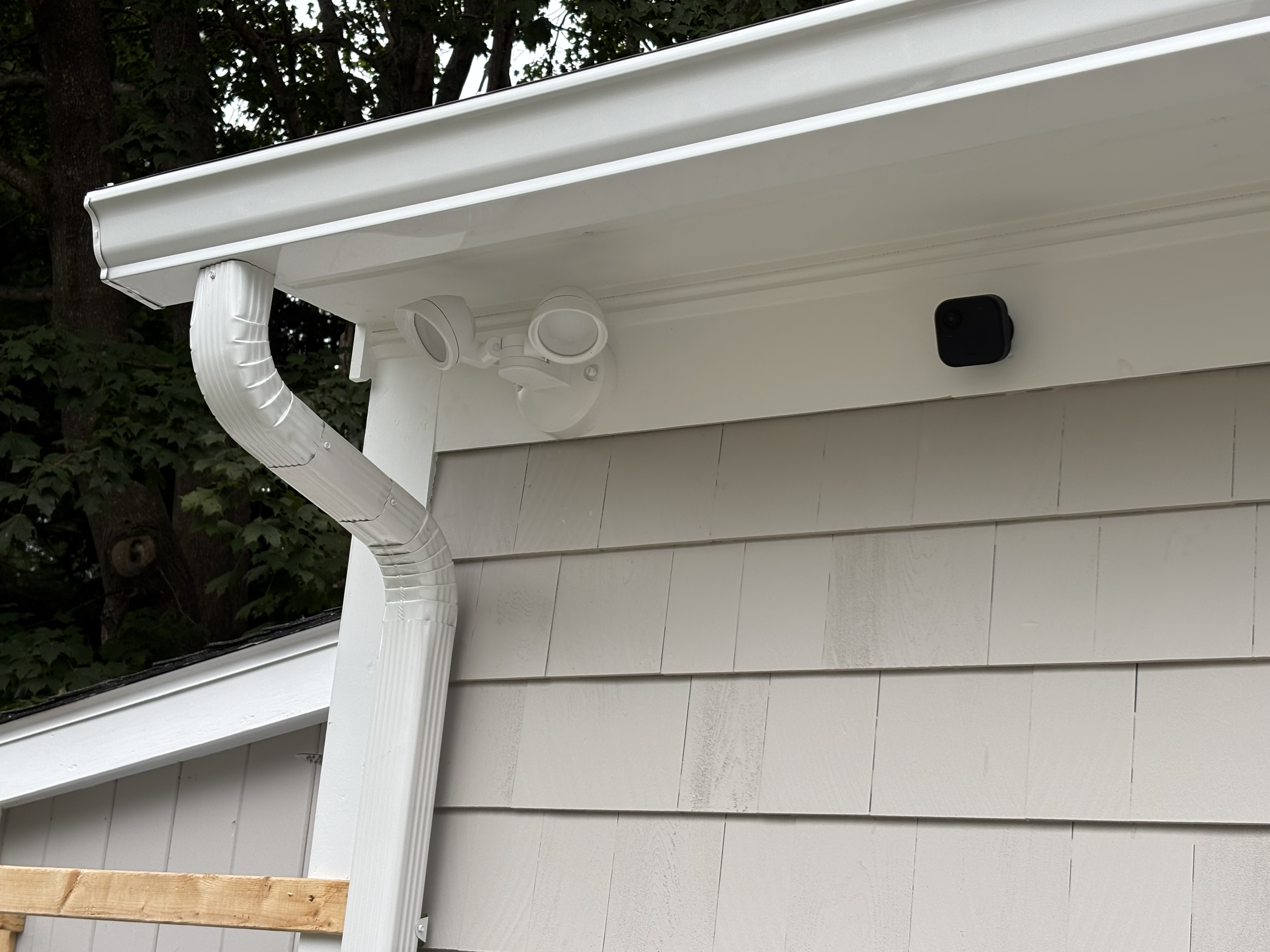 White gutter corner with downspout and security light